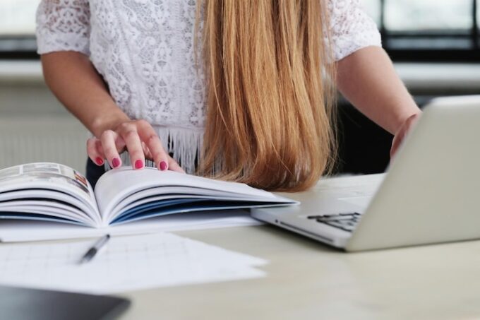 read book and type word on laptop